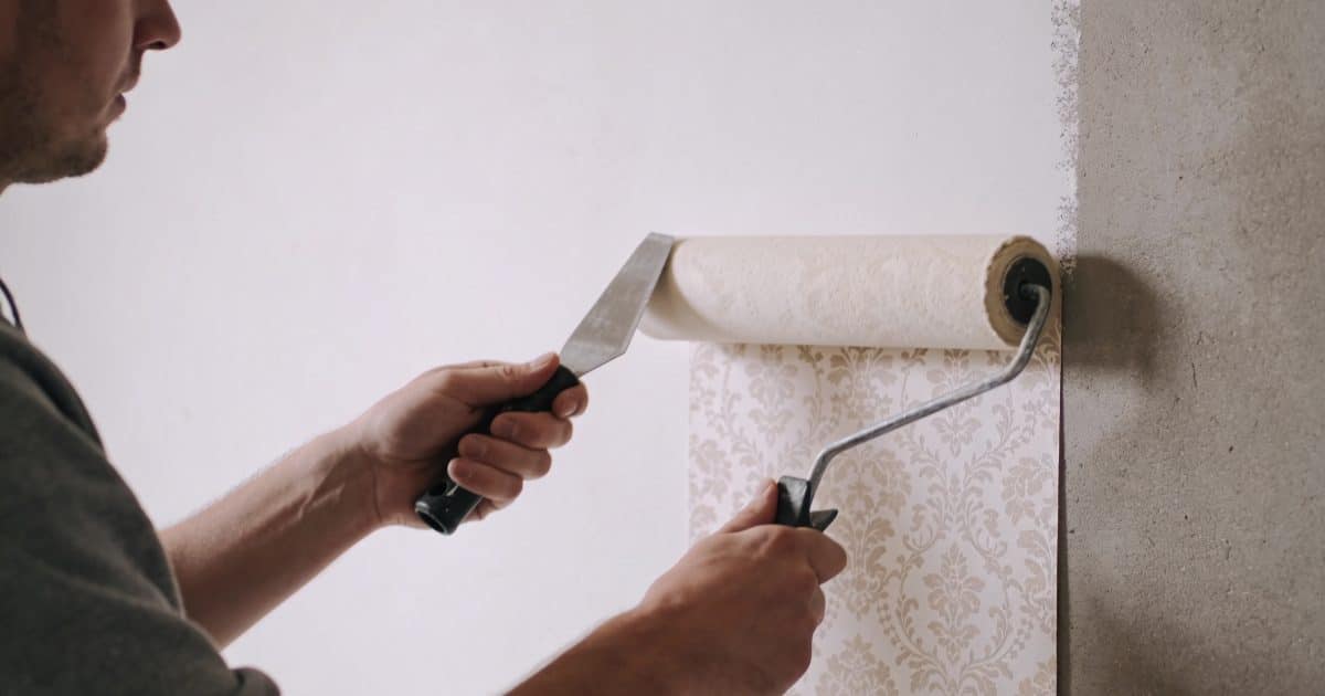 Une personne appliquant du papier peint sur un mur.
