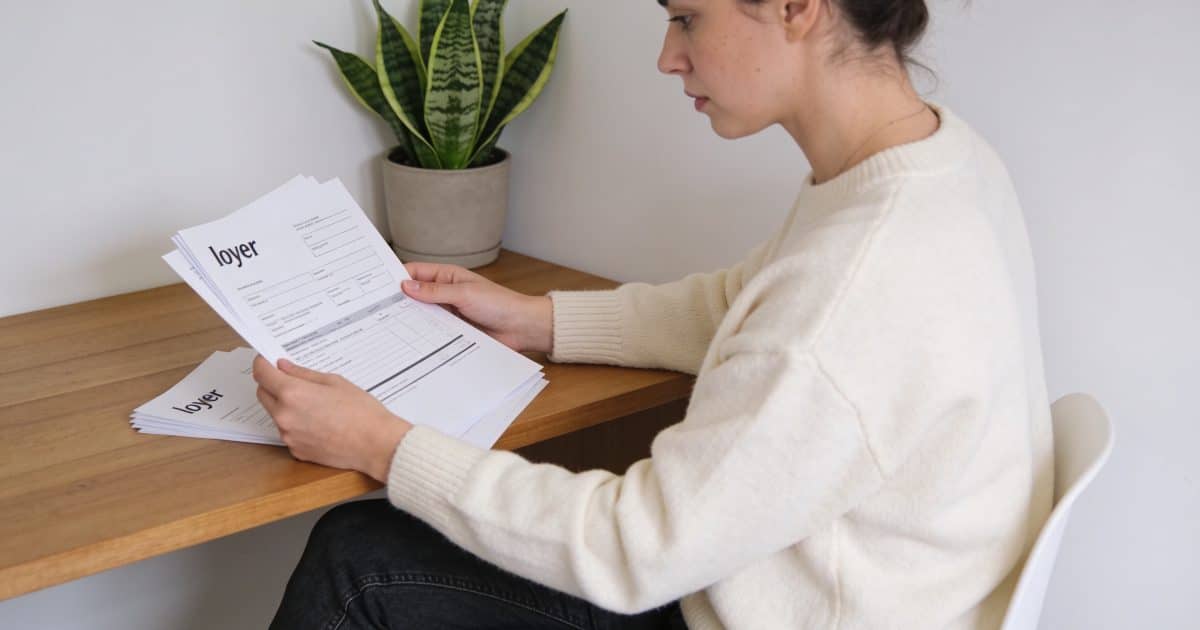 Femme regardant des documents avec des factures de loyer.